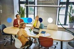 Group of people sitting at a oval table, having a meeting