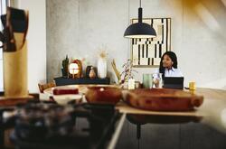 Man looking serious, sitting at a kitchen table with tablet.