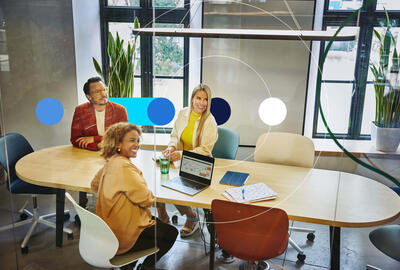 Group of people sitting at a oval table, having a meeting
