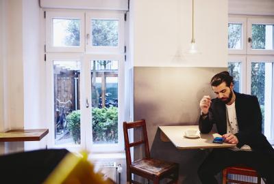 Man sitting at table with a coffee, looking seriously at his phone.