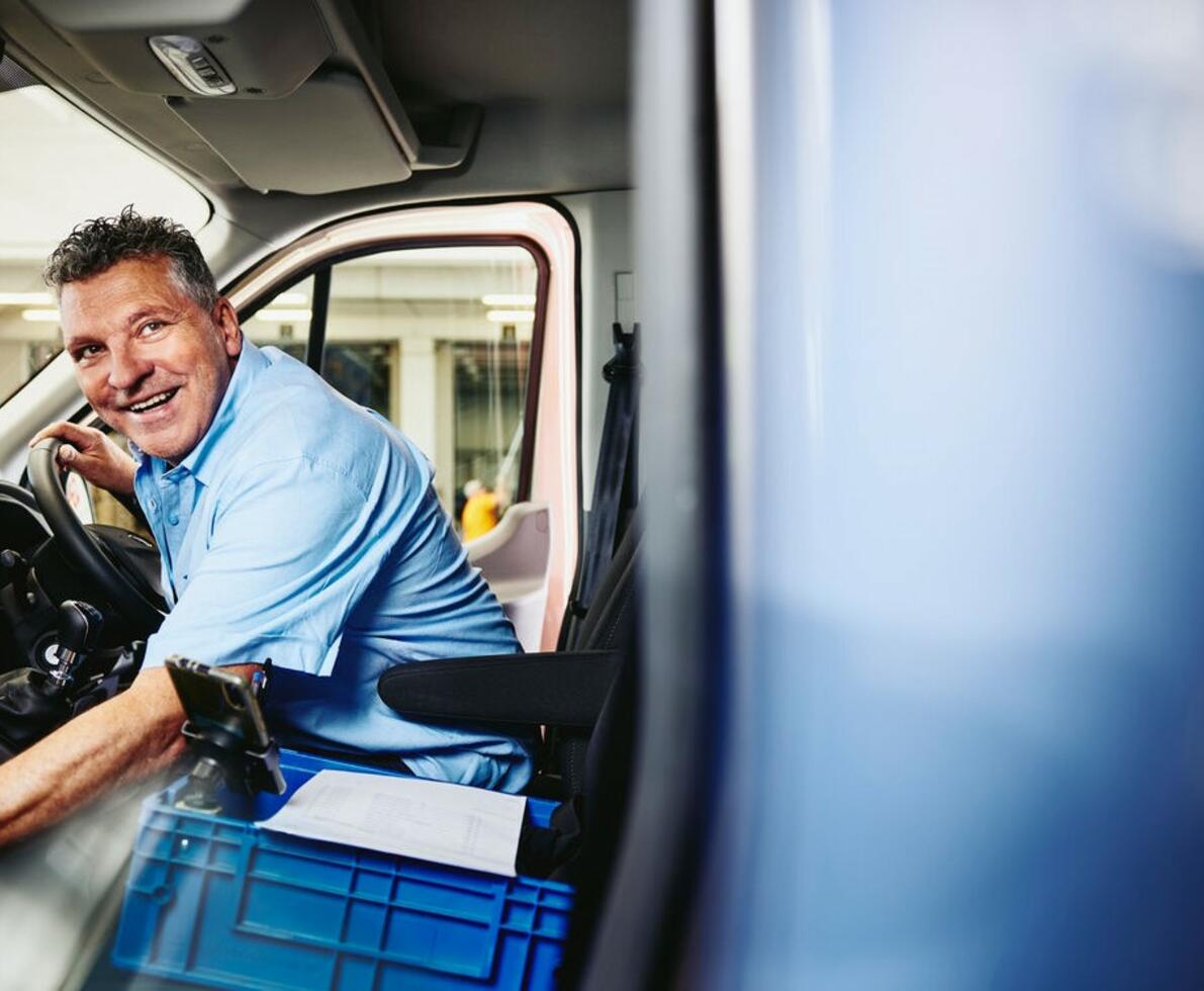 Smiling male sitting in driver's seat of a logistics truck