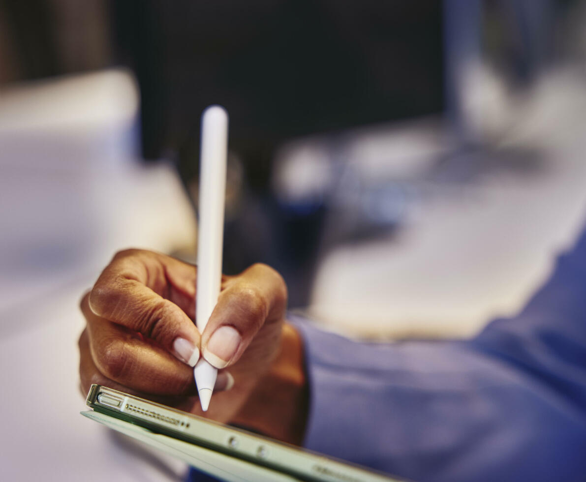 Close up of a hand holding a touch pen and a tablet